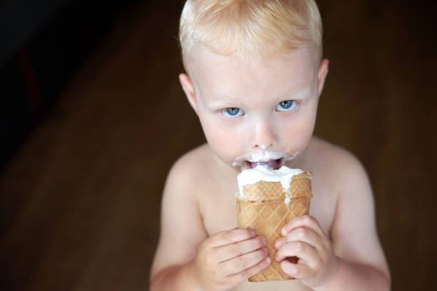 istock Little blue-eyed fair-haired boy eats ice cream. 1254957540