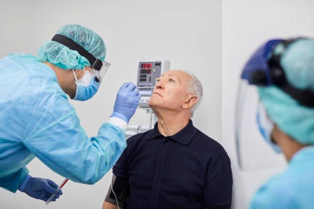 doctor taking coronavirus sample from male's nose, pcr. - nurse doctor scrubs male imagens e fotografias de stock