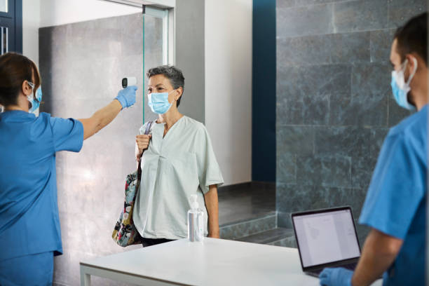 istock Nurse Checking Woman's Temperature at Counter 1254958367