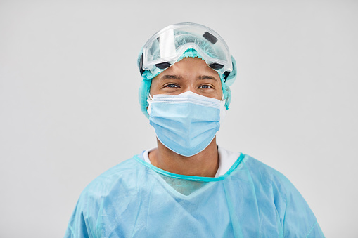 Portrait of male doctor wearing protective workwear. Close-up of essential service worker. He is against white background