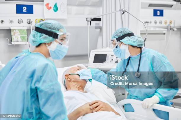 Female Doctor Talking With Patient Along Coworker Stock Photo - Download Image Now - Coronavirus, Hospital, Patient