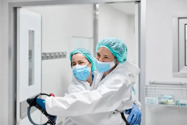 Photo of Happy Frontline Coworkers Embracing at Hospital