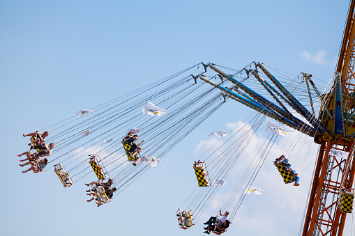 People flying in seats of carouesle high up in sky at fun fair Duesseldorf, scene at annual summer attraction at Rhine