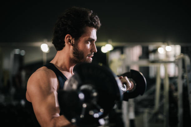 istock Handsome bearded young man with muscular body working out with barbell 1254961462