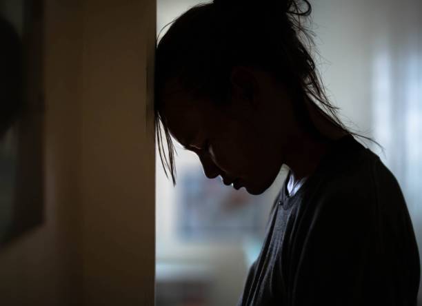 Sad distraught woman in her room at home. A woman suffering from deep depression and sorrow. sad girl crouching stock pictures, royalty-free photos & images