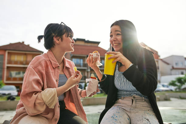 istock Charming young female friends having fun while eating fast food 1254964267