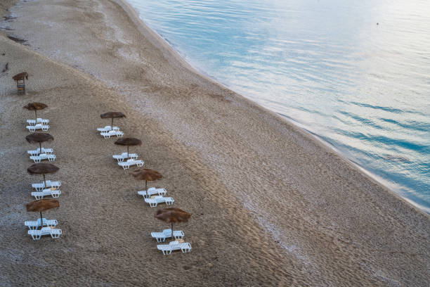 istock Straw sunshades and sunbeds on the empty sandy beach 1254964770