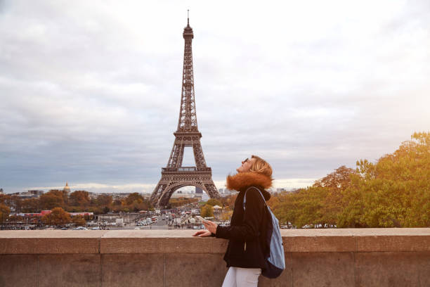 istock Girl using cellphone with Paris city background and Eiffel tower. 1254965499