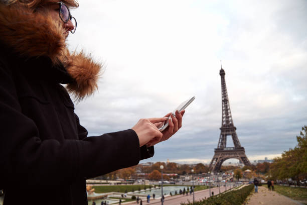 istock Girl using cellphone with Paris city background and Eiffel tower. 1254965552