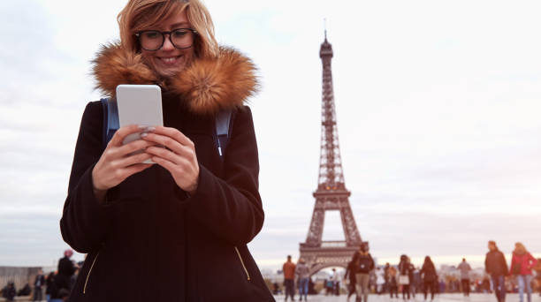 istock Girl using cellphone with Paris city background and Eiffel tower. 1254965597