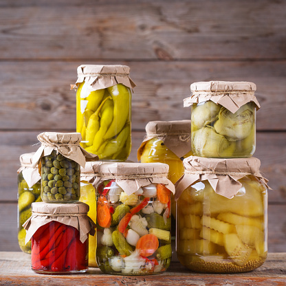 Preserved and fermented food. Assortment of homemade jars with variety of pickled and marinated vegetables on a wooden table. Housekeeping, home economics, harvest preservation