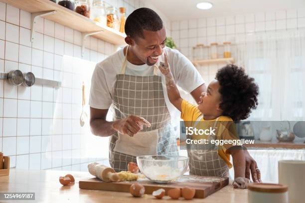 African Father And Son Enjoying During Bake Cookies At Home Together Stock Photo - Download Image Now