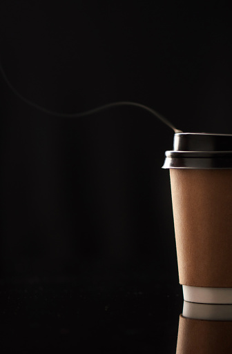 Closeup shot of steam rising from a paper cup filled with a warm beverage