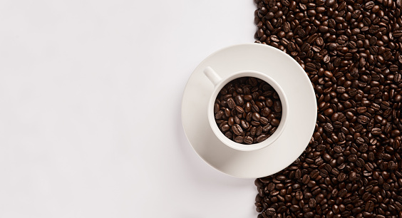 Closeup shot of a cup filled with coffee beans against a half-and-half background