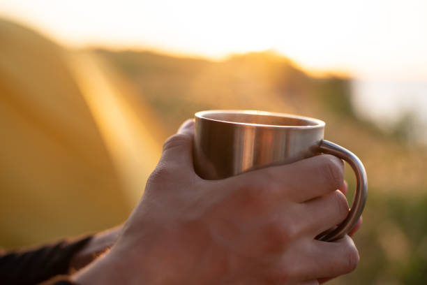 istock A man with a metal mug in his hands at sunset 1254974839