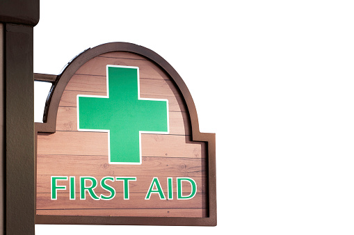 Wooden first aid sign on white background, green cross first aid.