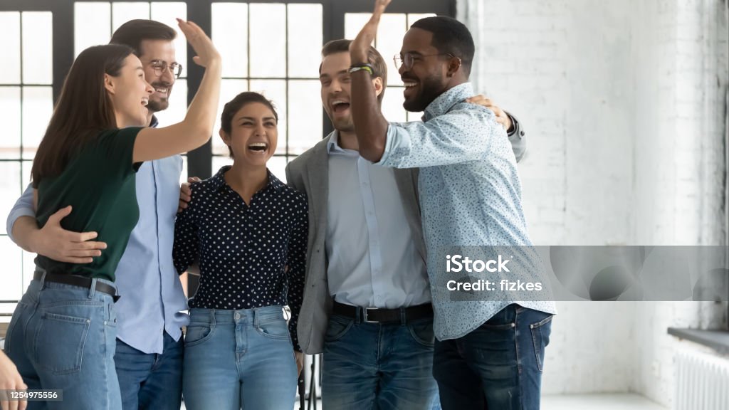 Empleados multiétnicos logran proyecto celebrando el éxito dando alto - Foto de stock de Trabajo en equipo libre de derechos