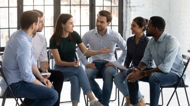 istock Six employees sit on chairs discussing taking part in seminar 1254975599