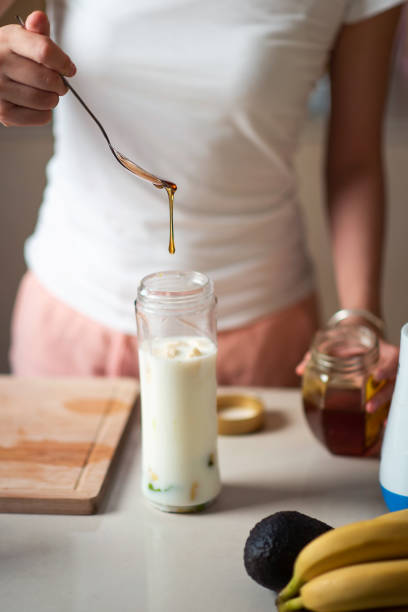 istock Woman adding honey while making avocado and banana smoothie for a healthy breakfast beverage 1254977031