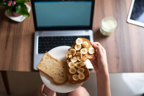 istock Woman having breakfast while working from the sofa at home first person view 1254977953