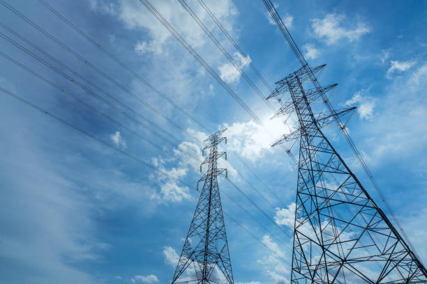 istock High voltage electric pylon and electrical wire against blue sky and white clouds. Bottom view of Electricity pylon with sunlight. High voltage grid tower with wire cable.  Power and energy concept. 1254979652