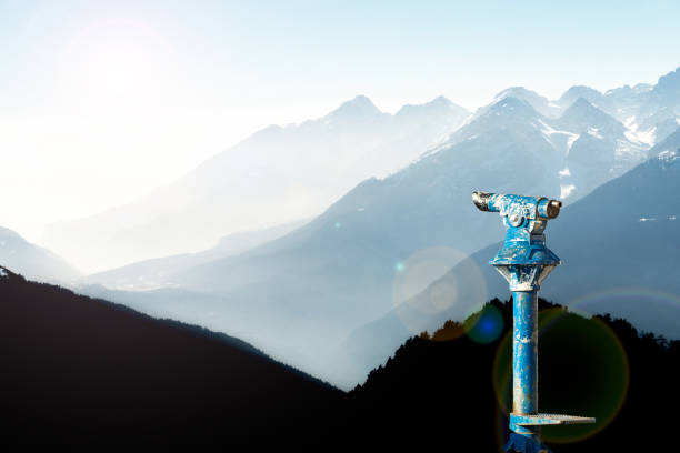 Public binoculars and Mountain Silhouettes at Sunrise. Foresight and vision for new business concepts and creative ideas. Alps, Trentino, South Tyrol, Italy. stock photo