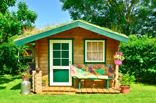 A light green and wooden small shed, gardenhouse, with a bench some tools around it stock photo