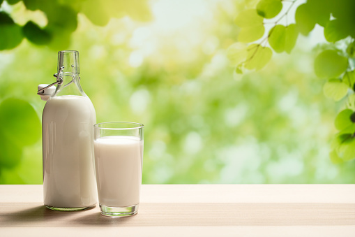 A glass bottle of milk and a full glass of milk