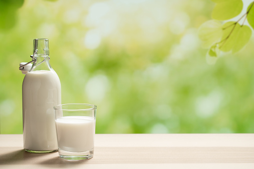 A glass bottle of milk and a full glass of milk