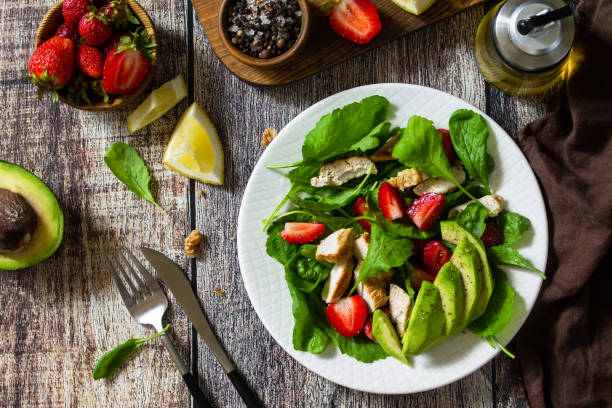istock Lunch for keto. Summer salad with strawberries, grilled chicken and avocado on a rustic table. Top view flat lay background. 1254985472