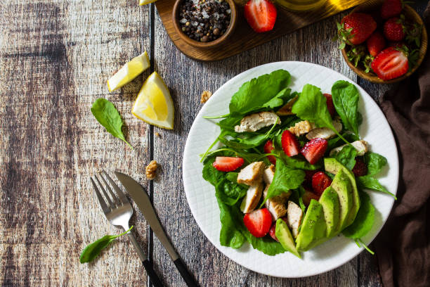 istock Lunch for keto. Summer salad with strawberries, grilled chicken and avocado on a rustic table. Top view flat lay background. Copy space. 1254985480