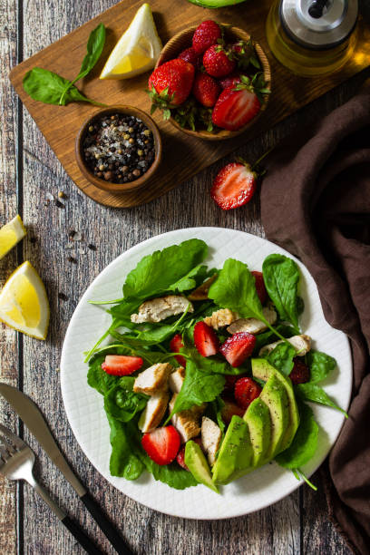 istock Lunch for keto. Summer salad with strawberries, grilled chicken and avocado on a rustic table. Top view flat lay background. 1254985485