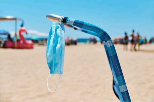 istock surgical mask hanging on a deck chair on the beach 1254988383