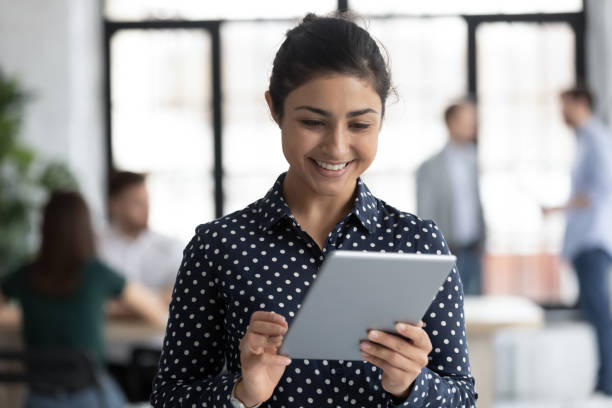 istock Indian employee holding tablet device surfing web in office 1254989192