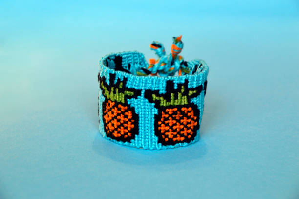 istock Woven friendship bracelet with alpha pattern pineapples handmade of thread on blue background 1254992593