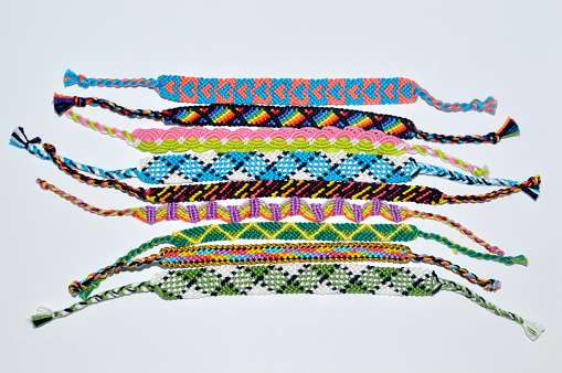 Multi-colored woven friendship bracelets handmade of embroidery bright thread with knots isolated on white background