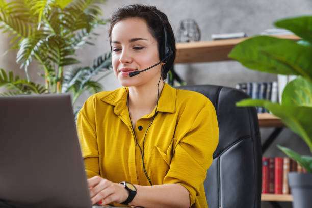 istock Beautiful freelancer female talking in online video conference using headset with microphone and laptop in home office desktop 1254993973