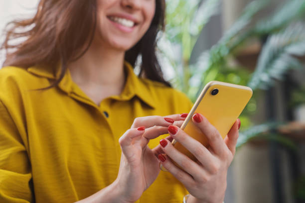 обрезанное изображение счастливой девушки с помощью смартфона устройства во время охлаждения дома - телефон стоковые фото и изображения