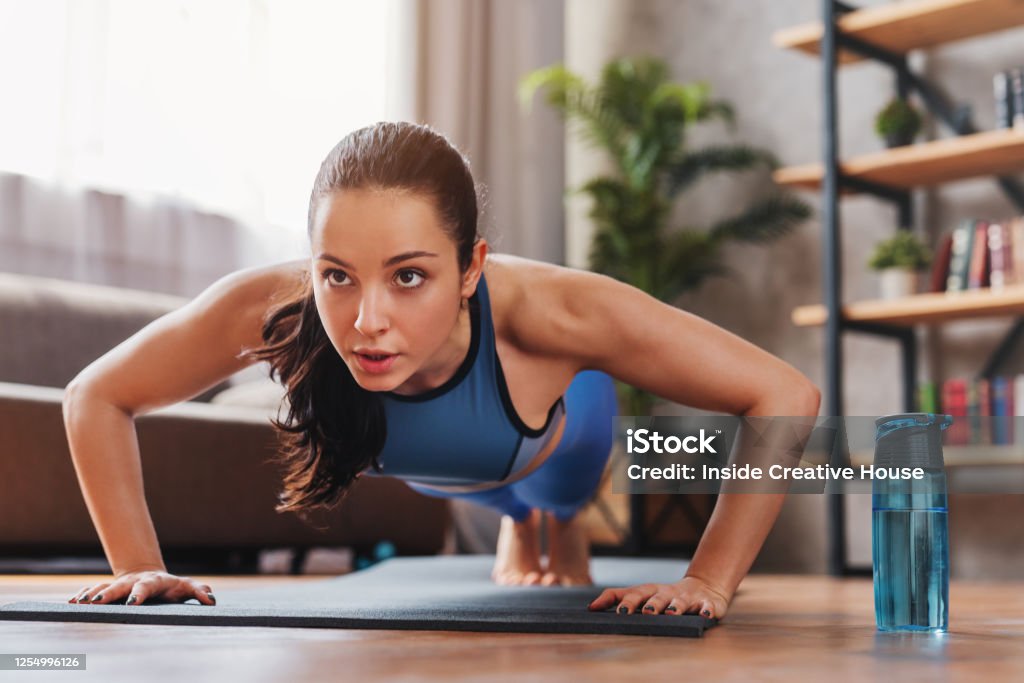 Beautiful young sports lady doing push ups while workout at home Exercising Stock Photo