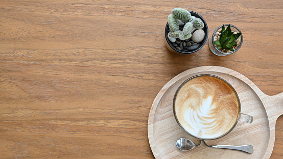 Top view a cup of coffee and cactus on wooden table in home office.