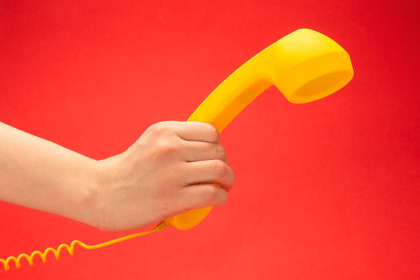 istock Yellow handset on a red background in woman hand. 1255003224