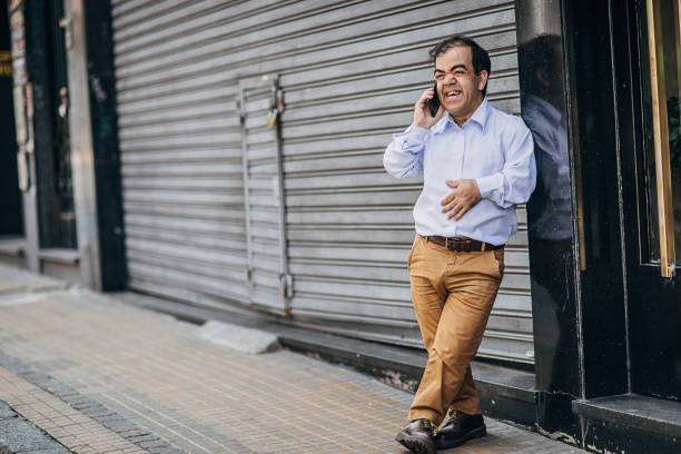Gentleman talking on mobile on the street One man, little adult gentleman standing on the city street, talking on mobile phone. dwarf stock pictures, royalty-free photos & images