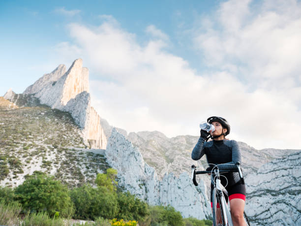 istock Female cyclist with bike drinking water from bottle 1255009029