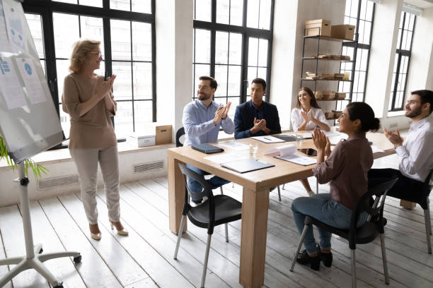 istock Diverse employees applauding, thanking middle aged mentor for presentation 1255011642