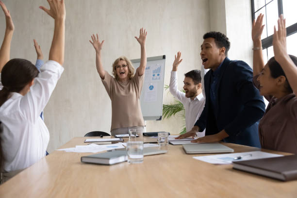 istock Excited diverse employees team celebrating success, raising hands and screaming 1255011662