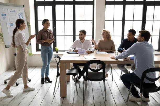 istock Two diverse businesswomen giving flip chart presentation at meeting 1255011665