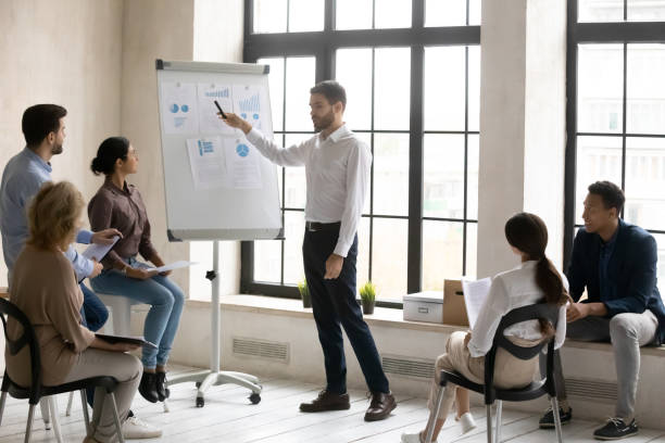 istock Businessman presenting project statistics on flip chart at briefing 1255011700