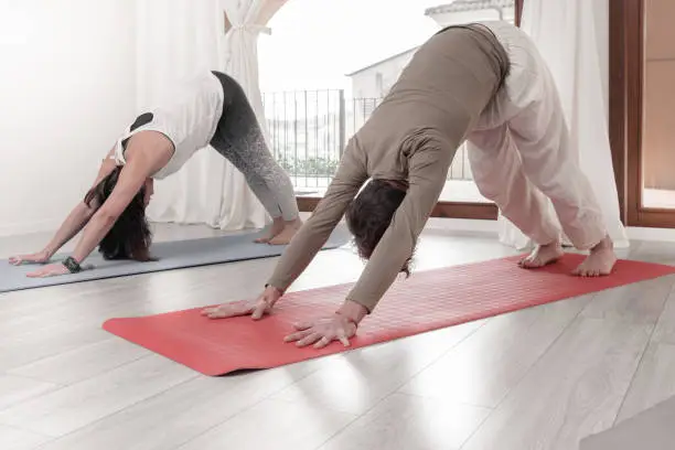 Photo of Group of people practicing Yoga. Adho Mukha Shvanasana. Dog pose. Sun Salutation or Surya Namaskar