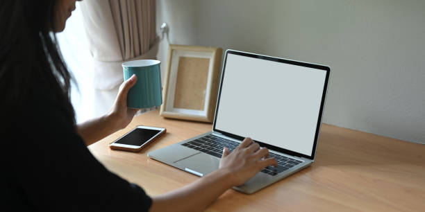 ein abgeschnittenes bild einer frau benutzt einen weißen computer-laptop mit leerem bildschirm, während sie im wohnzimmer sitzt. - laptop adult curtain business stock-fotos und bilder