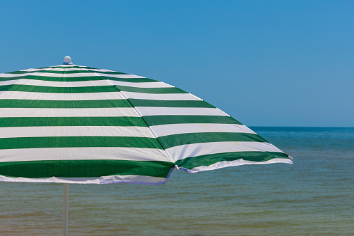 Beach striped umbrella on a background of blue sky and sea